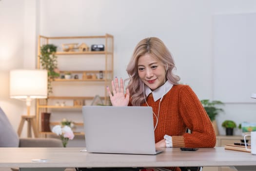 Beautiful young accountant wearing headphones holds financial meeting with company team online with laptop from home..