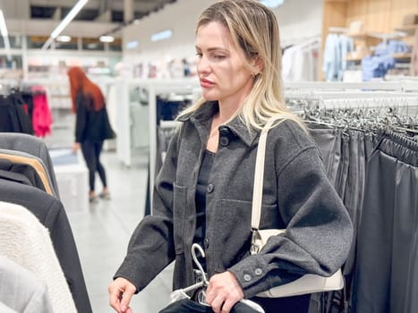 a young woman chooses a shirt in a clothing store . High quality photo