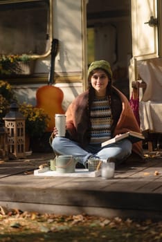 A fashionable, bohemian lady, rocking a hippie look, savors a hot drink on the house terrace. High quality photo