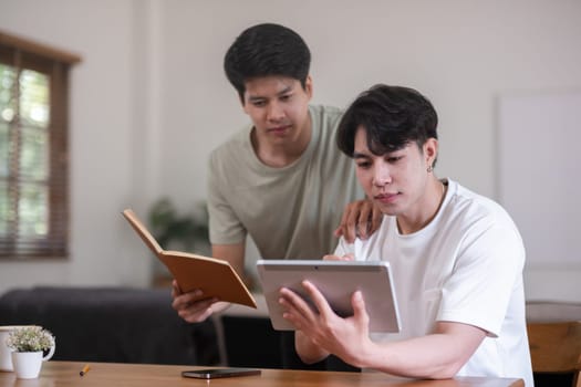 A male lgbt couple is studying together while studying online at home to prepare for an online exam..