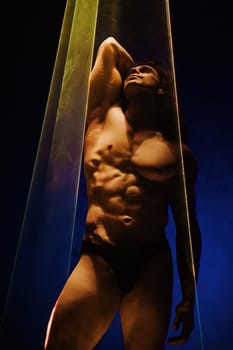 Muscular strong guy with naked torso abs under colorful illumination, laser in smoky room. Sporty man body, projection illusion