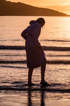 Silhouette of female swimmer going into the Atlantic ocean in Ireland.