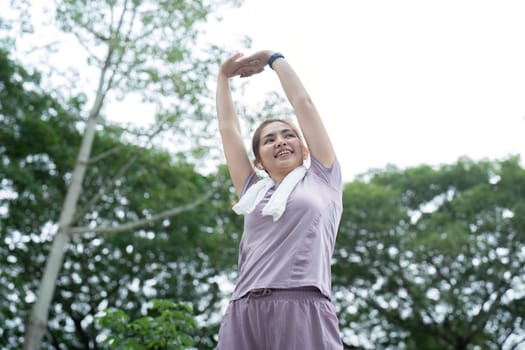 Asian woman stretching after a run in a park.