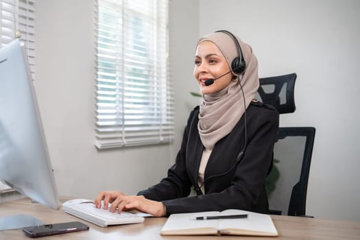 Muslim female call center employee wearing hijab Talking with customers on laptop in customer service office.