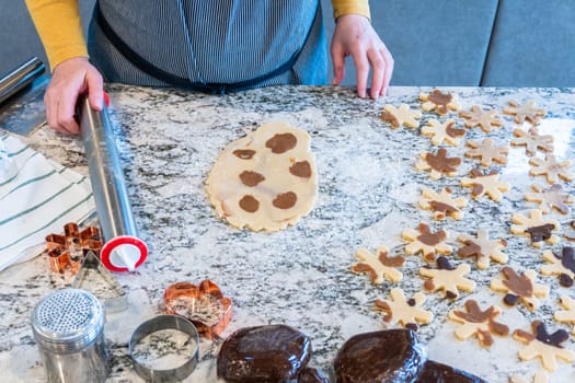 In a contemporary white kitchen, gingerbread cookie dough is skillfully rolled out, setting the stage for a delightful holiday treat.