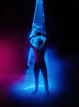 Sporty handsome man with long hair, naked torso abs portrait under colorful illumination, laser light, neon smoke club. Projection illusion mapping. Futuristic model.