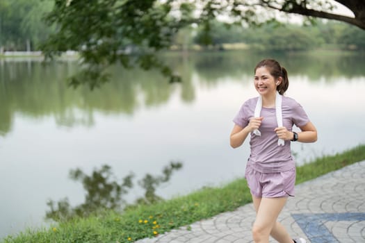 Young asian woman enjoying a morning run in a park. Workout exercise in the morning. Healthy and active lifestyle concept.