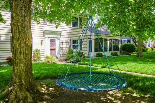 Classic American suburban home in Fort Wayne, lush yard with a playful tree swing, embodying tranquility and family life.