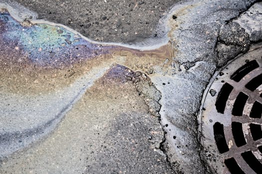 Oil stain on the asphalt surface seeps into the storm drainage system
