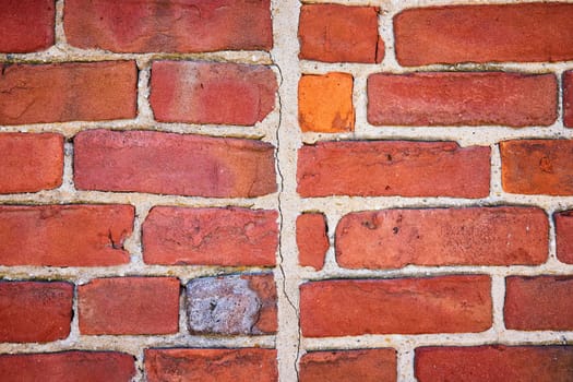 Close-up of a weathered brick wall in Fort Wayne, showcasing varied textures and a standout orange brick.