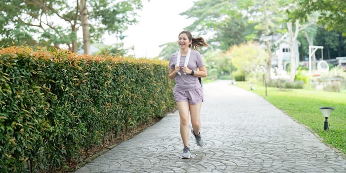 Asian fitness female sportswoman runner doing morning jogging exercise training outdoor. Happy smile woman asian running in the park.