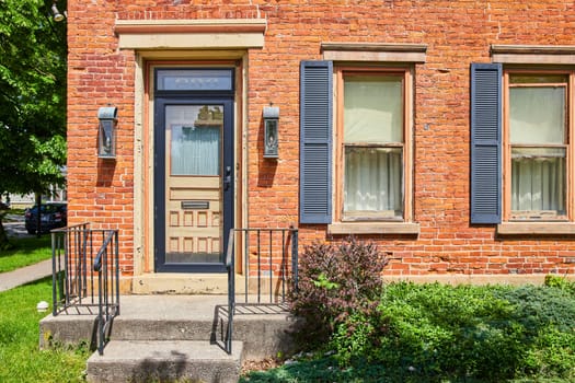 Charming brick home with blue shutters and lush greenery in historic Fort Wayne, Indiana. Perfect for real estate and lifestyle themes.