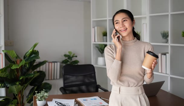 Asian businesswoman talking on the phone, having an online business meeting in a modern home office..