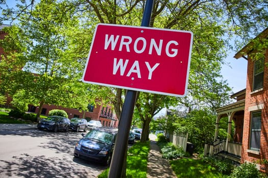 Vivid WRONG WAY sign on a sunny suburban street in Fort Wayne, emphasizing safety and direction.