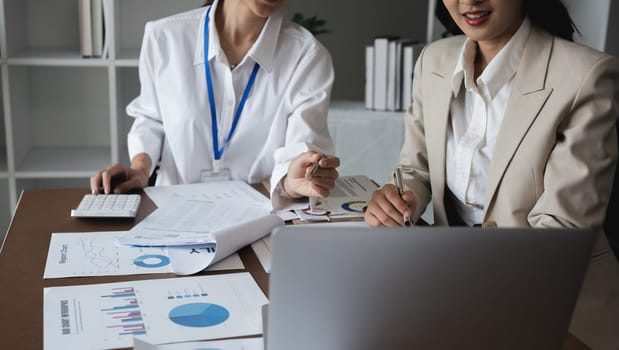 Two Asian businesswomen analyzing financial reports and graphs. Concept of financial analysis and business planning.