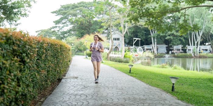 Asian fitness female sportswoman runner doing morning jogging exercise training outdoor. Happy smile woman asian running in the park.