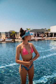 A trendy and sophisticated woman looks stunning in her blue bikini by the poolside. High quality photo