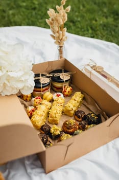 A charming picnic box brimming with an assortment of delectable pastries and fresh, colorful flowers, set against a natural backdrop.