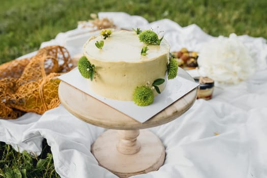 A tempting cake perched elegantly on a table amidst the lush green grass, inviting indulgence in a serene outdoor setting.