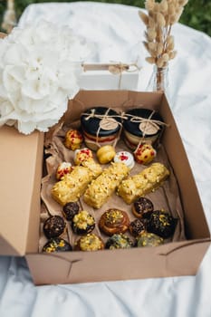 A box overflowing with a variety of delicious pastries surrounded by a vibrant assortment of fresh flowers.