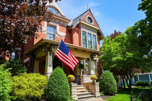 Charming Victorian brick house with American flag, sunny suburban Fort Wayne setting.
