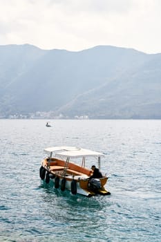 Man is sailing on a small excursion boat on the sea. Back view. High quality photo