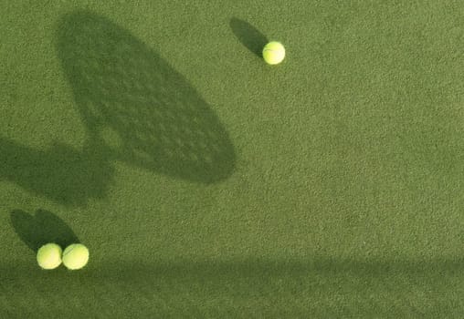 Closeup view of a paddle racket and balls in a padel tennis court near the net. Green background with white lines. Sport, health, youth and leisure concept. Sporty equipment. White lines in background. High quality photo