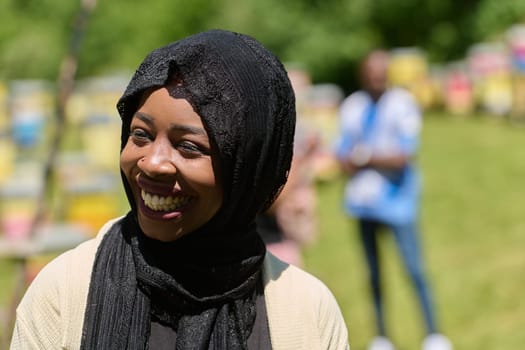 A Middle Eastern Muslim woman in a hijab beams with a radiant smile in a picturesque natural apiary, exuding joy and harmony