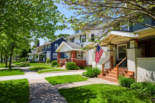 Charming suburban street in Fort Wayne with townhouses and American flag, symbolizing community and pride.