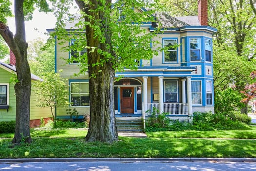 Sunny Victorian home in Fort Wayne's historic West Central neighborhood, surrounded by lush greenery.