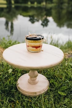 A white cake stand displays a jar of vibrant red jam, creating a minimalist and elegant scene.