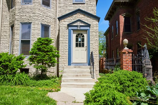 Charming townhouse with blue door nestled in historic Fort Wayne neighborhood, showcasing urban architectural diversity.