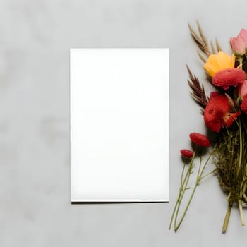 An overhead view of a blank white card with scattered flowers around it.
