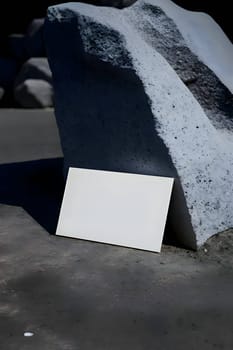A blank white sheet of paper placed on a background of a large stone.