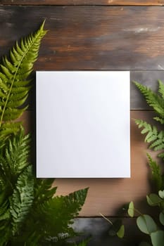 A pristine white sheet, a blank canvas, resting on a wooden table adorned with lush ferns surrounding it.