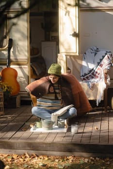 A stylish, bohemian lady, dressed in a hippie outfit, sips a warm beverage on the terrace. High quality photo