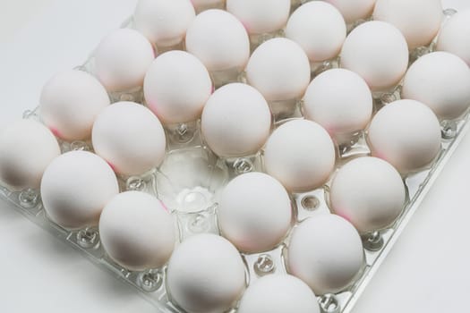 Raw white chicken eggs in tray on white background. Organic food from nature.