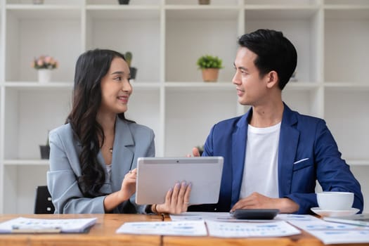 A young businessman and a female Asian accountant are discussing financial accounting and business planning together in the office..