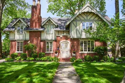 Elegant Tudor-style home in Fort Wayne, surrounded by lush gardens and historical charm, perfect for suburban living.