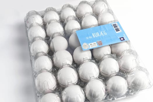 Raw white chicken eggs in tray on white background. Organic food from nature. Denmark - March 4, 2024.