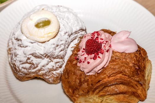 Delicious Mardi Gras buns with cream on a white plate.