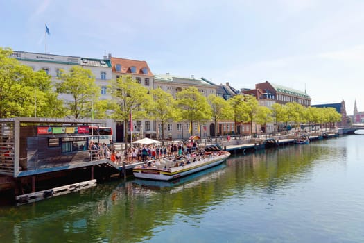A boat with people is sailing along a water canal in the city. Copenhagen, Denmark - November 17, 2023