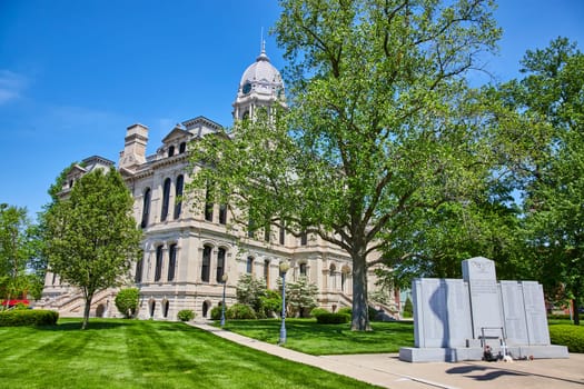 Majestic Kosciusko County Courthouse with war memorial, under clear blue skies in Warsaw, Indiana.