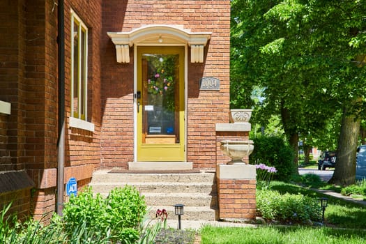 Charming red brick home with yellow door in historic Fort Wayne, symbolizing security and suburban elegance.