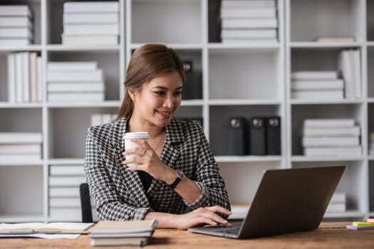 Beautiful determined business woman working using laptop and calculator calculating turnover in modern office.