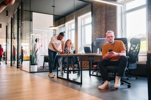 A diverse group of business professionals collaborates in a modern startup coworking center, utilizing a mix of paper-based and technological tools such as mobile phones and computers .