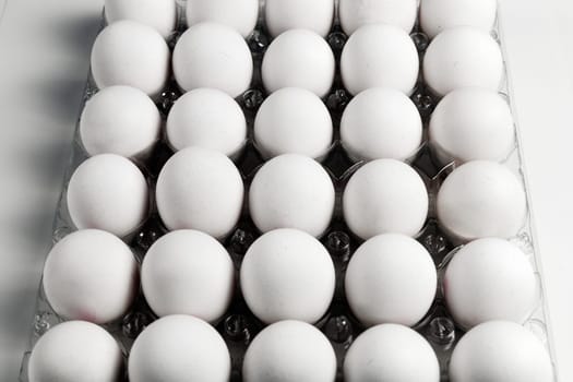 Raw white chicken eggs in tray on white background. Organic food from nature.