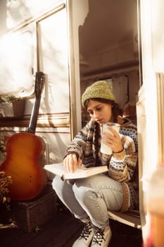 A stylish, bohemian lady, dressed in a hippie outfit, sips a warm beverage on the terrace. High quality photo