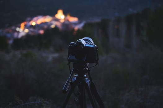 Travel photography. World photography Day. A digital camera placed on tripod, capturing the Andalusian medieval city of Quesada in mountains Sierra de Cazorla at dawn. Blurred mountains on background.