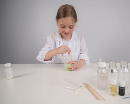 Caucasian girl doing chemical experiments on a white background. Making slime